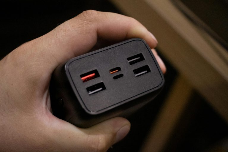 Close-up shot of a hand holding a multi-USB port power adapter, highlighting its ports.